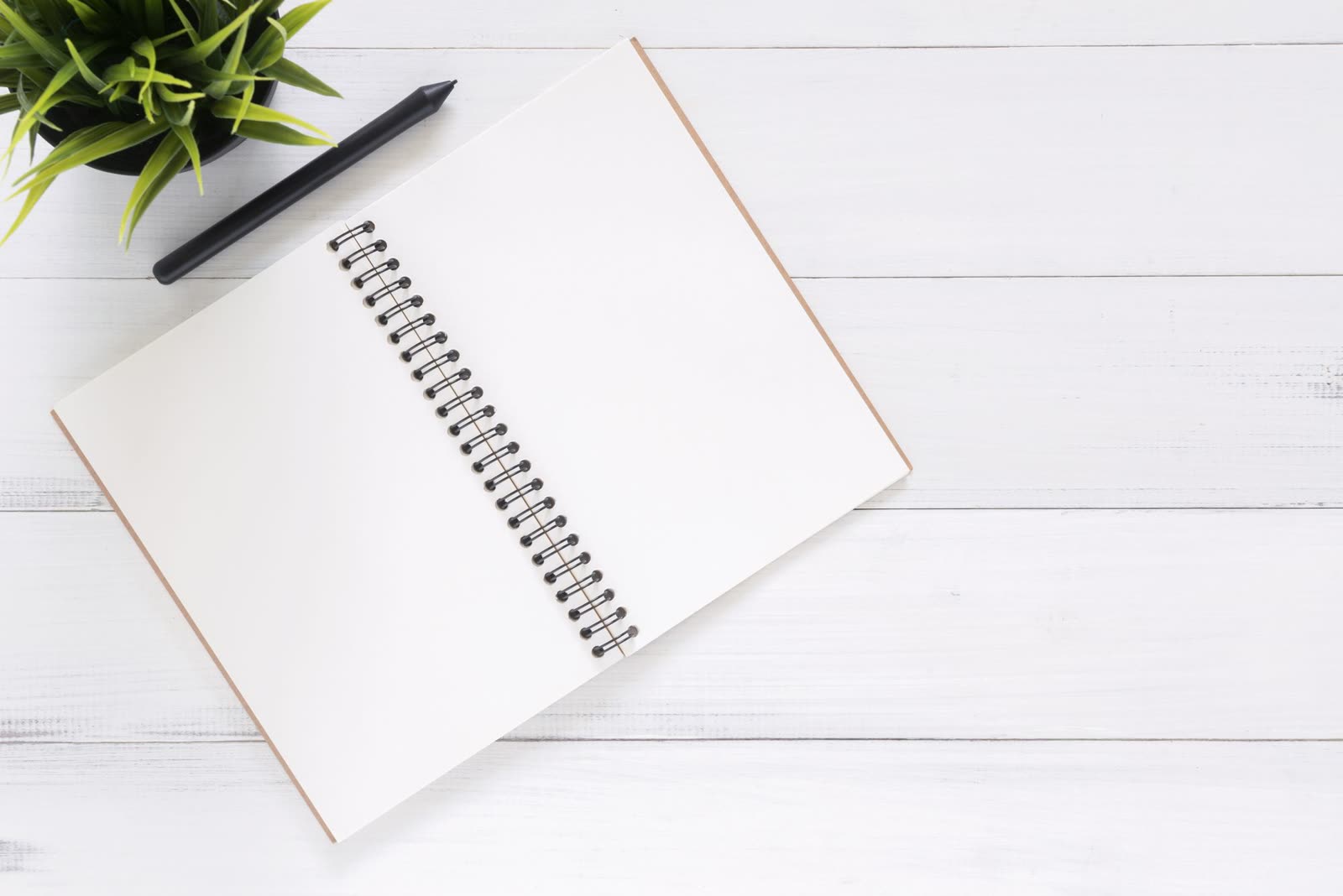 Un carnet ouvert et un stylo, sur une table claire.